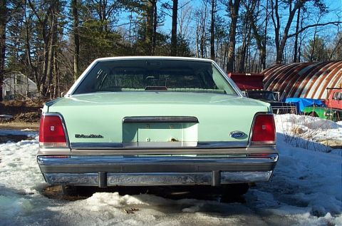 2001 Ford Crown Victoria - The rear of a light green Ford Crown Victoria is shown parked in a snowy area with trees in the background.