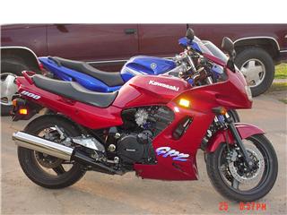 1992 Ford Bronco - A red Kawasaki GPz 1100 motorcycle is parked in front of a maroon Ford Bronco. The motorcycle is shown from a three-quarter front angle, hi…