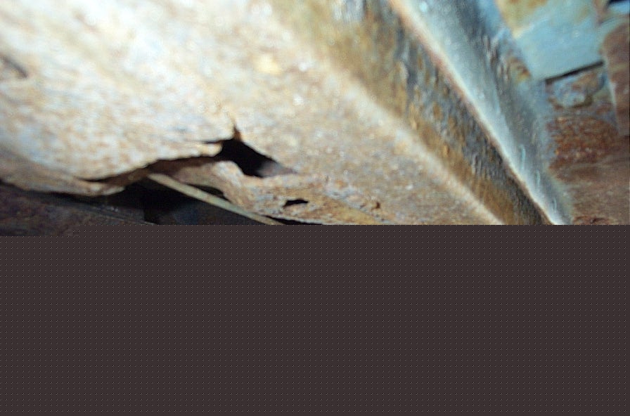 rusted metal frame with holes, showing undercarriage damage