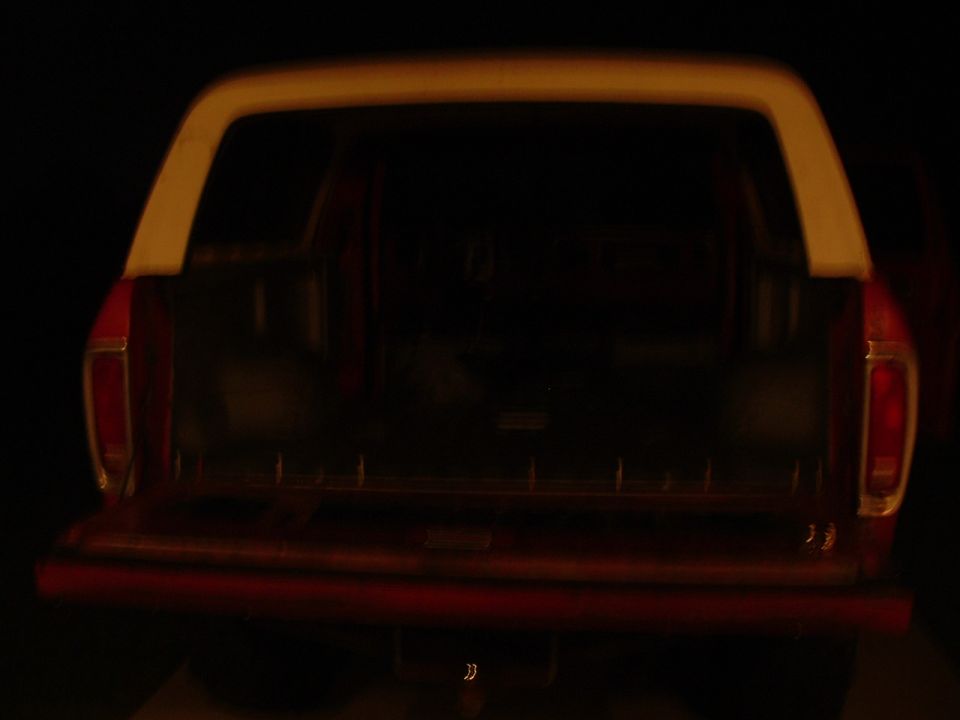 Rear view of a red station wagon SUV with tailgate open and white roof.