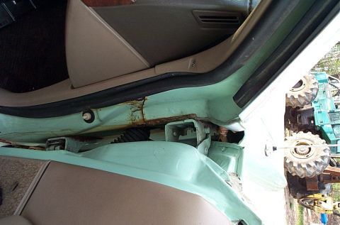 2001 Ford Crown Victoria - The interior door frame shows significant rust and damage, with other vehicles visible in the background.