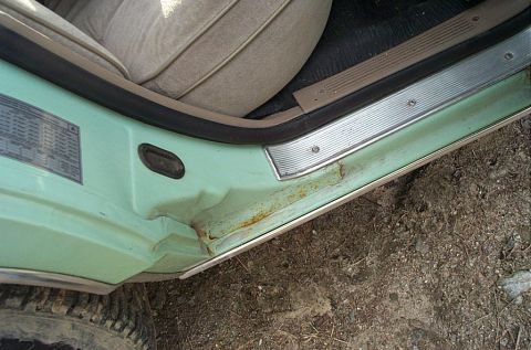 2001 Ford Crown Victoria - Close-up of a damaged interior door sill and seat in a vehicle.