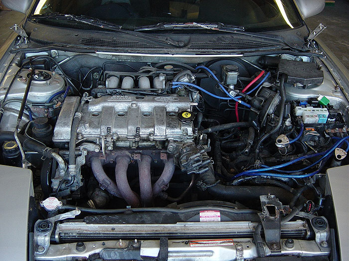 Transverse V6 engine bay with intake manifold removed, exposing head and exhaust manifold