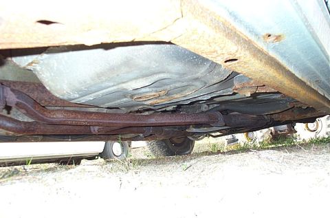 2001 Ford Crown Victoria - The underside of a vehicle displays significant rust on its exhaust components and frame.