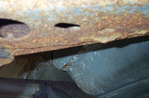 2001 Ford Crown Victoria - The undercarriage of a vehicle shows extensive rust damage on its structural components.