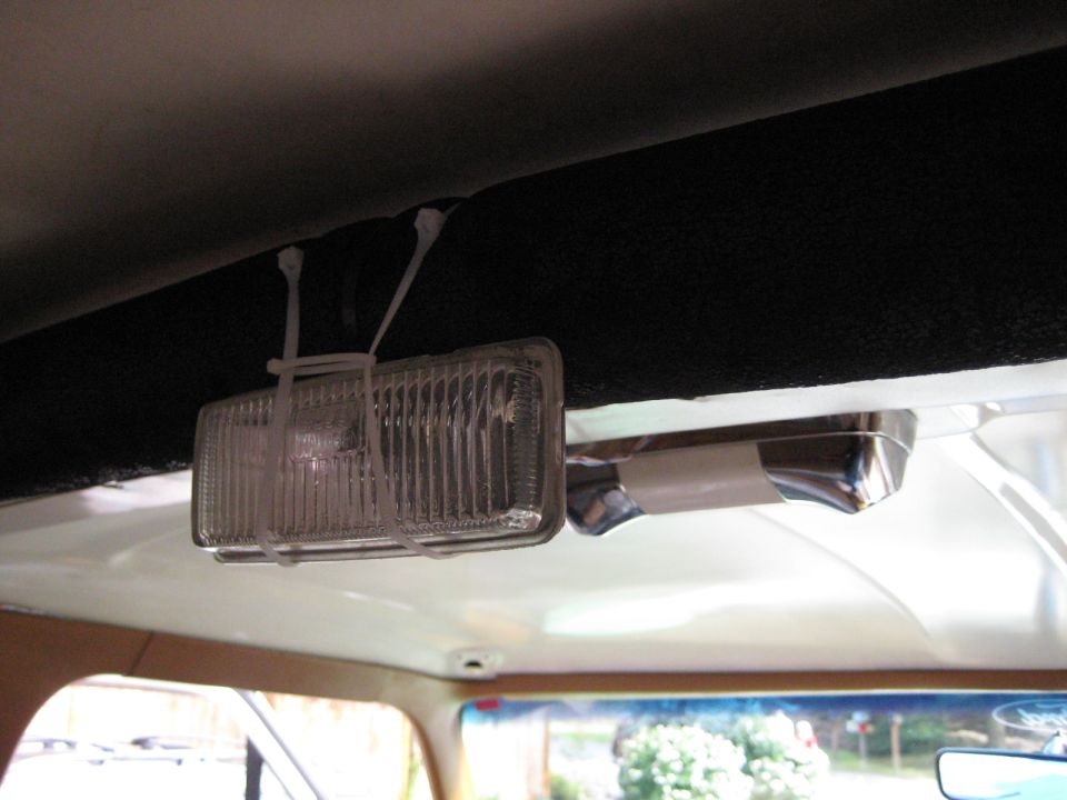 Interior view of a vehicle's headliner with a zip-tied light fixture and grab handle.