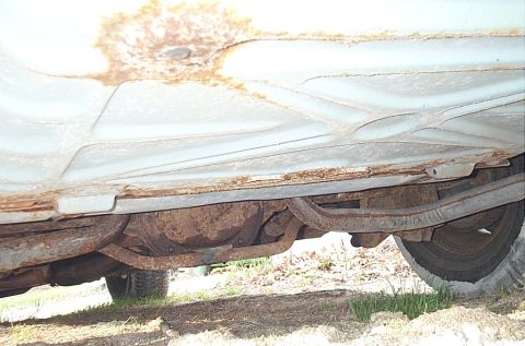 2001 Ford Crown Victoria - Undercarriage view of a vehicle, showing significant rust on the frame and body panels.
