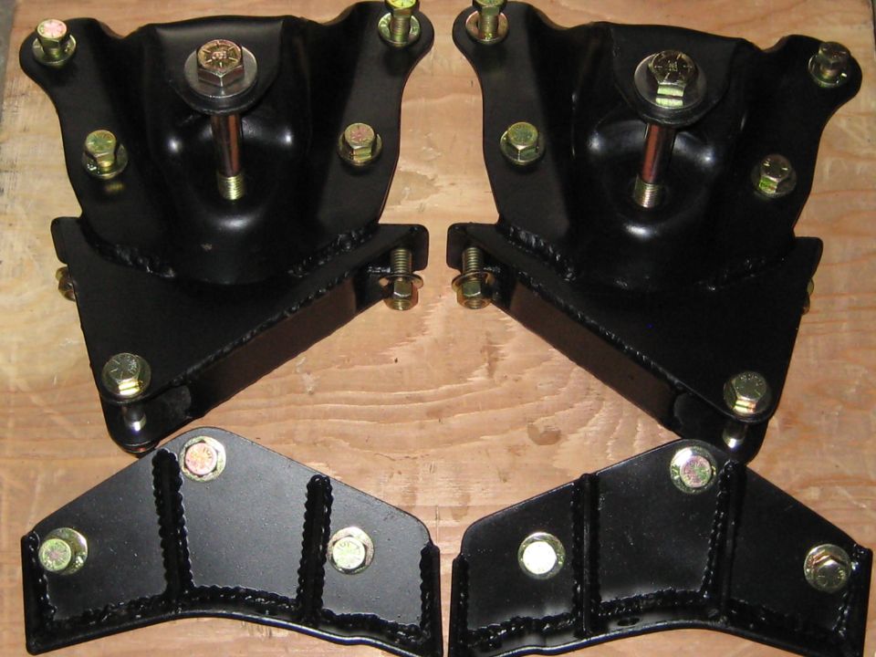Two black steel engine mounts and two black steel brackets with gold bolts.