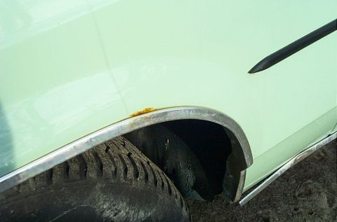 2001 Ford Crown Victoria - A close-up view of a car's fender reveals a tire and some rust near the wheel well.