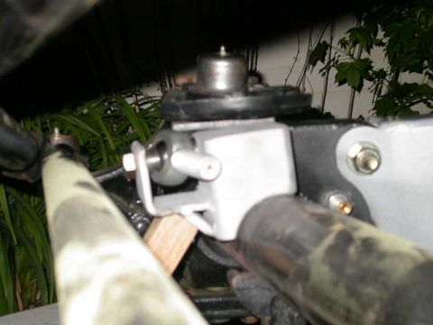 1990 Ford Bronco - Close-up view of a modified suspension component, likely part of a steering or linkage system, on a vehicle. The part is silver and black,…