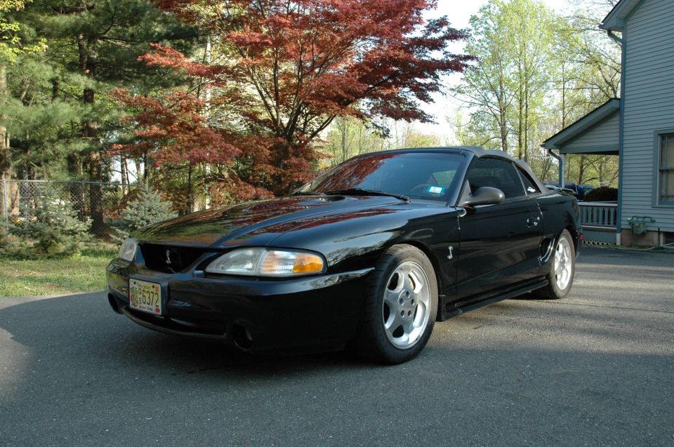 Black Ford Mustang convertible parked on driveway.
