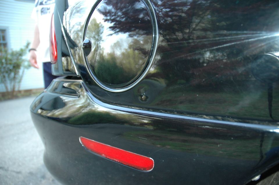 Black car rear quarter panel with dent and red reflector