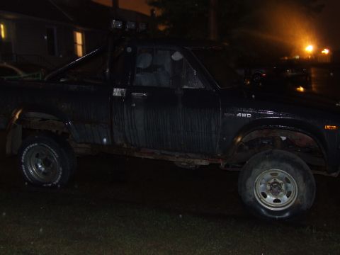 1990 Ford Bronco - A dark 1990 Ford Bronco is seen from the side under artificial lighting.