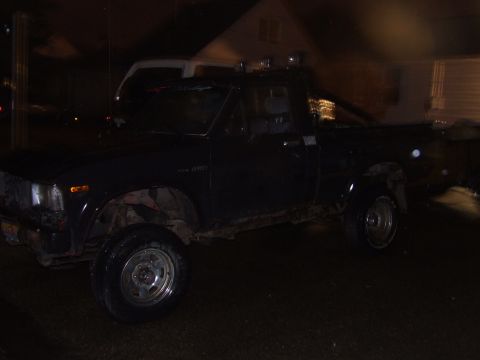 1990 Ford Bronco - A dark-colored Toyota pickup truck is parked outside at night, showing its 4WD badging.