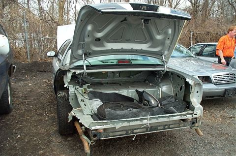 2001 Ford Crown Victoria - A silver 2001 Ford Crown Victoria is seen from the rear with its trunk open, revealing a spare tire and other items.