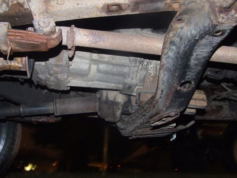 1990 Ford Bronco - The underside of a vehicle reveals its mechanical components, including the transmission and suspension system.