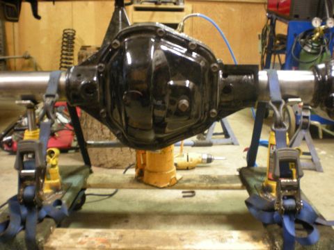 1993 Ford Bronco - A rear axle assembly is shown supported by jack stands and straps in a workshop setting.