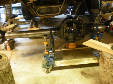 1993 Ford Bronco - A vehicle's rear axle assembly is supported by a jack stand in a garage setting.