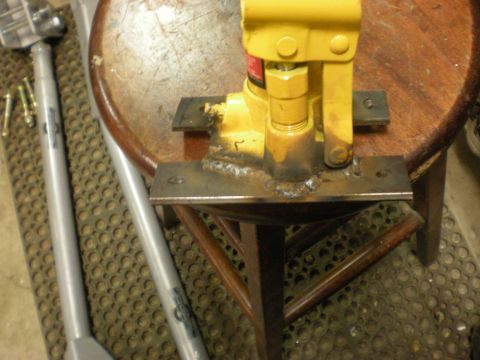 1993 Ford Bronco - Hydraulic bottle jack mounted on a stool with metal plates and visible bolts.
