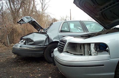 2001 Ford Crown Victoria - Two damaged sedans are parked side-by-side, both with their hoods open, indicating recent mechanical issues or accidents.