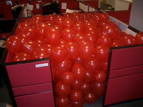 2000 Mercury Grand Marquis - An office cubicle is completely filled with red balloons, obscuring the workspace within.