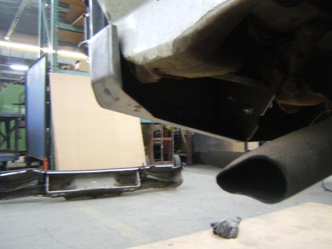 1993 Ford Bronco - Close-up view of a vehicle's exhaust pipe and rear bumper assembly, with a large panel in the background.