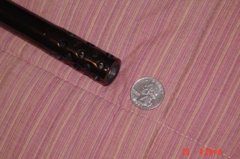 1946 Ford F1 - A close-up view of a black gun barrel with a perforated muzzle, placed next to a U.S. quarter for scale.