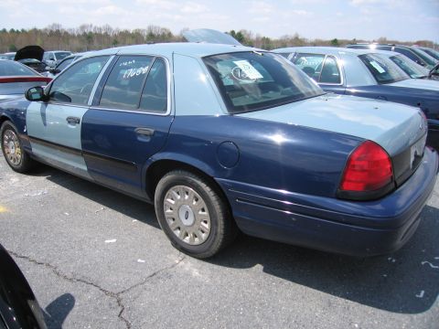 2001 Ford Crown Victoria - This sedan has a dark blue lower half and a lighter blue upper half, with a white sticker on the rear window.