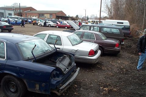 2001 Ford Crown Victoria - A blue sedan with its trunk open is parked in a lot with other vehicles. The car appears to be a 2001 Ford Crown Victoria.