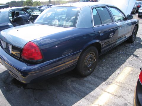 2001 Ford Crown Victoria - This Ford Crown Victoria appears to be in a junkyard or impound lot, with its hood open and visible damage on the side.