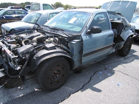 2001 Ford Crown Victoria - A light blue 2001 Ford Crown Victoria is shown with significant front-end damage and its hood open.