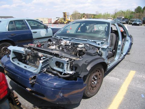 2001 Ford Crown Victoria - Wrecked 2001 Ford Crown Victoria in a salvage yard, with another police car visible to the left.