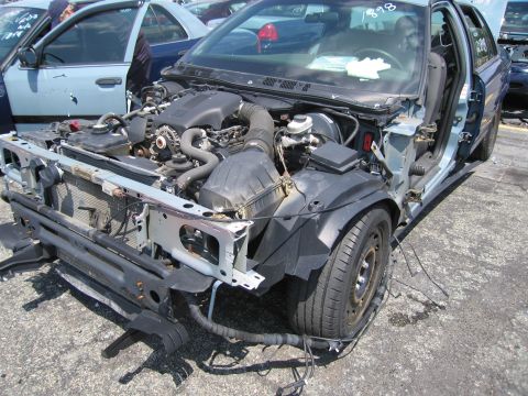 2001 Ford Crown Victoria - The front of a 2001 Ford Crown Victoria is shown with its hood removed, revealing the engine compartment and missing parts.
