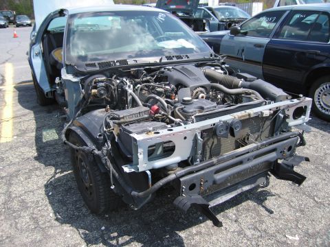 2001 Ford Crown Victoria - The front end of a car is shown with its hood open and engine exposed, indicating it has been dismantled or is undergoing repairs.