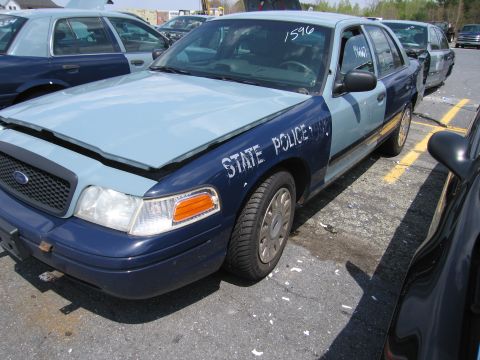 2001 Ford Crown Victoria - Two-tone Ford Crown Victoria police car, one with 'STATE POLICE' markings, parked in a lot.