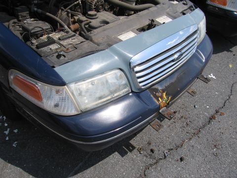 2001 Ford Crown Victoria - The front of a blue and light blue 2001 Ford Crown Victoria is visible with its hood open, revealing the engine compartment.