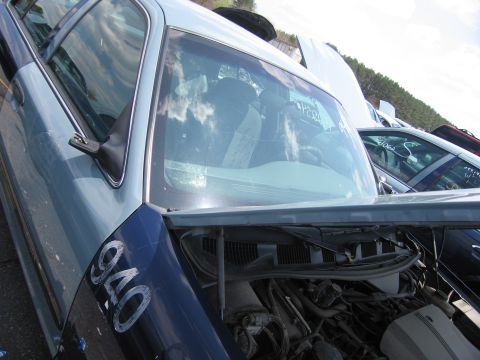 2001 Ford Crown Victoria - This 2001 Ford Crown Victoria, likely a former police vehicle, is seen in a junkyard with its hood open and number 940 visible on the fende…