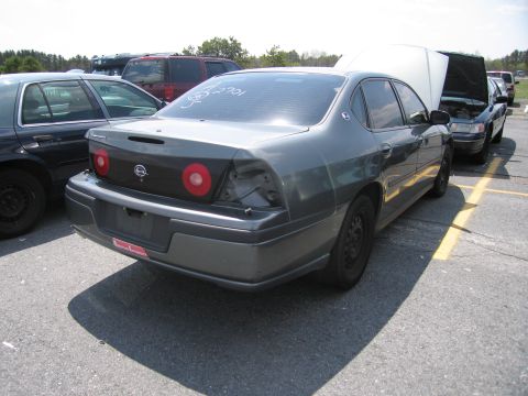 2001 Ford Crown Victoria - Rear view of a dark gray sedan with a missing taillight, parked in a lot with other vehicles.