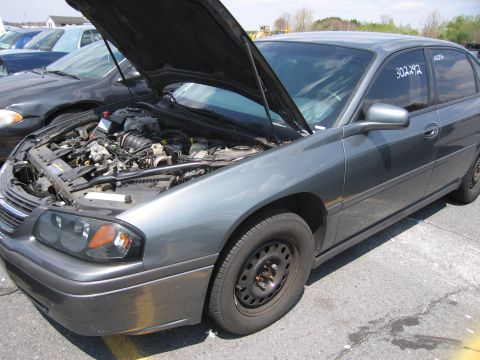 2001 Ford Crown Victoria - A gray sedan with its hood open, revealing the engine compartment, parked outdoors.