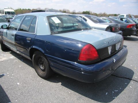 2001 Ford Crown Victoria - Rear view of a two-tone Ford Crown Victoria parked in an outdoor lot with other vehicles.