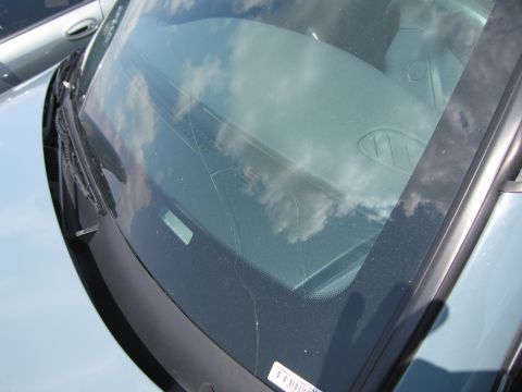 2001 Ford Crown Victoria - The windshield of a light blue vehicle displays significant cracks and reflections of the sky.
