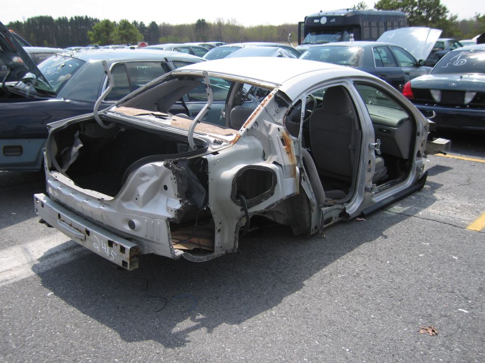 Silver sedan, stripped of most body panels, viewed from the rear