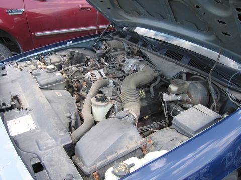 2001 Ford Crown Victoria - The engine bay of a blue car is shown, with a red Ford Expedition parked behind it. The engine appears to be from a 2001 Ford Crown Victori…