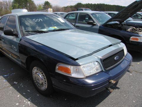 2001 Ford Crown Victoria - This Ford Crown Victoria has a two-tone paint job and a visible number on the windshield, with another vehicle in the background.