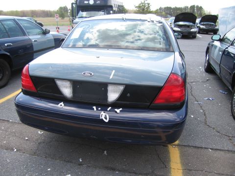 2001 Ford Crown Victoria - Rear view of a 2001 Ford Crown Victoria showing taillights and bumper, with other cars nearby.
