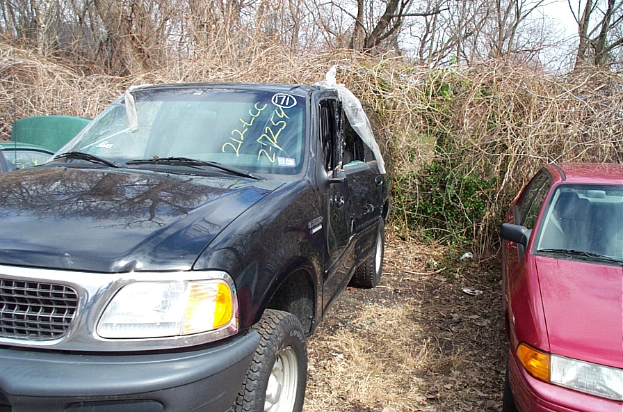 Black Ford Expedition with cracked windshield and plastic covering the driver's side window