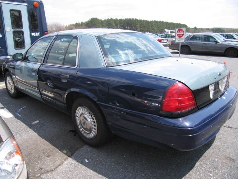 2001 Ford Crown Victoria - Rear view of a two-tone 2001 Ford Crown Victoria police car in a parking lot.