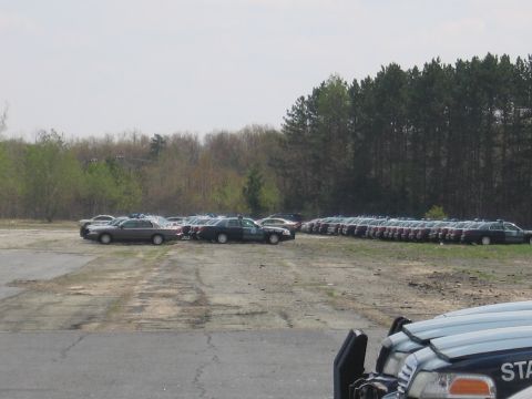 2001 Ford Crown Victoria - Many police cars are parked in a lot, with a line of them stretching into the distance.