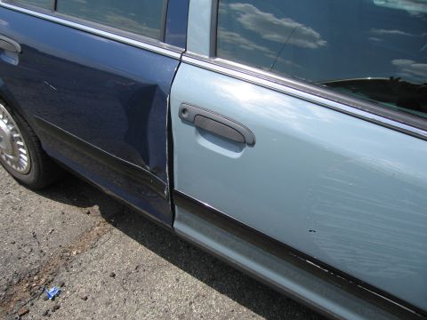 2001 Ford Crown Victoria - The vehicle has significant damage to the rear door, with a noticeable dent and misalignment.