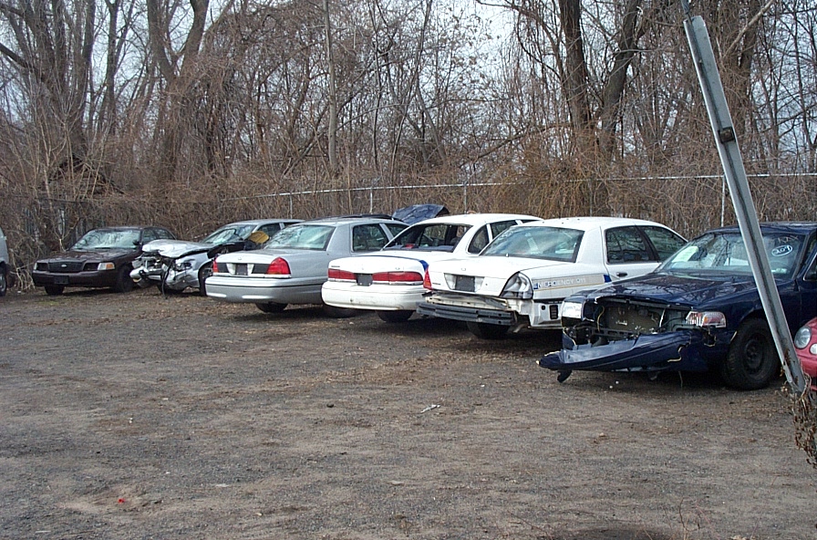 Several damaged Ford Crown Victorias parked in a lot